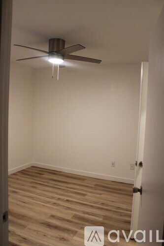 A room with a ceiling fan and wooden flooring.