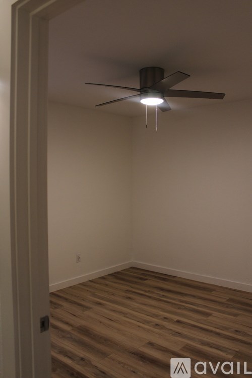 A room with a ceiling fan and wooden flooring.