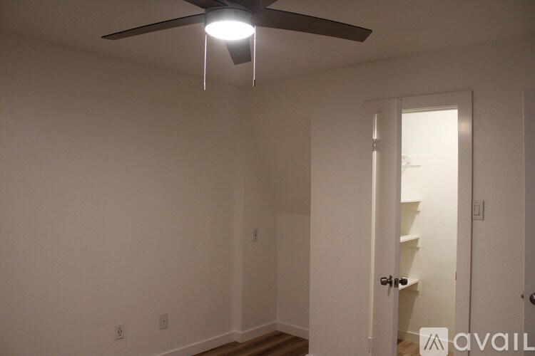A room with a ceiling fan and a door leading to another room.