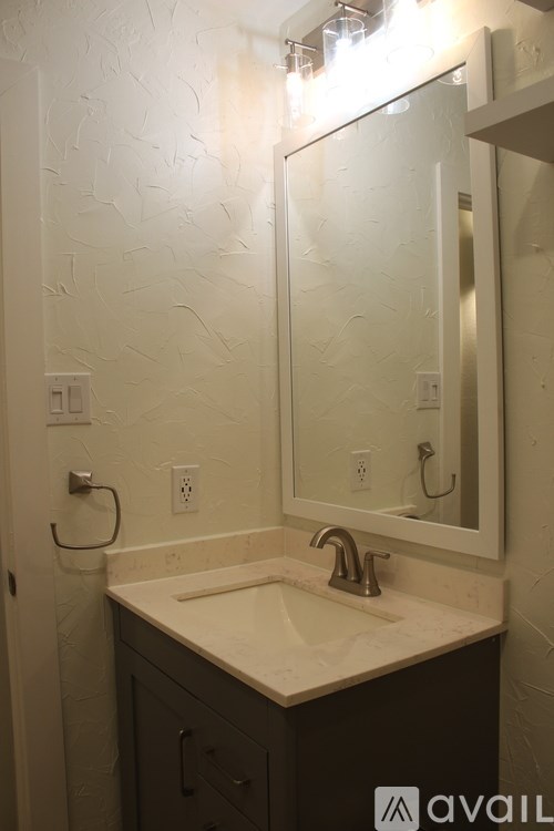 A bathroom with a sink, mirror, and cabinets.