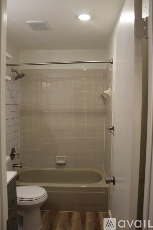 A bathroom with a white toilet and a beige tub.