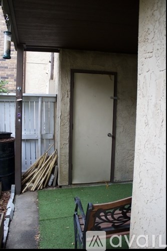 A brown bench sits on a green mat outside a door.