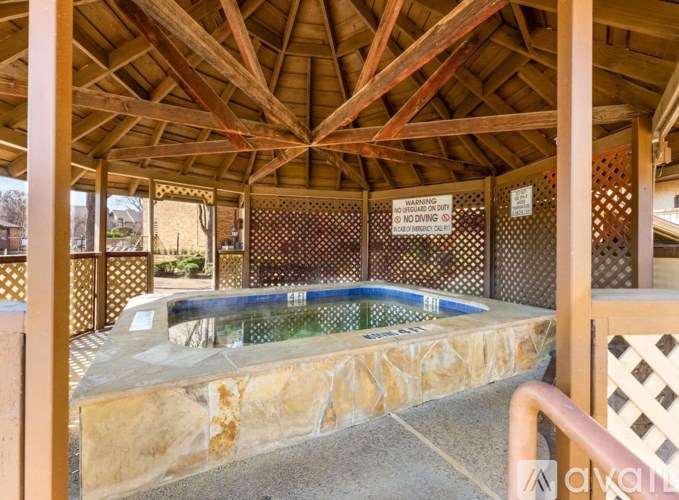 A hot tub is surrounded by a stone wall and a wooden deck.