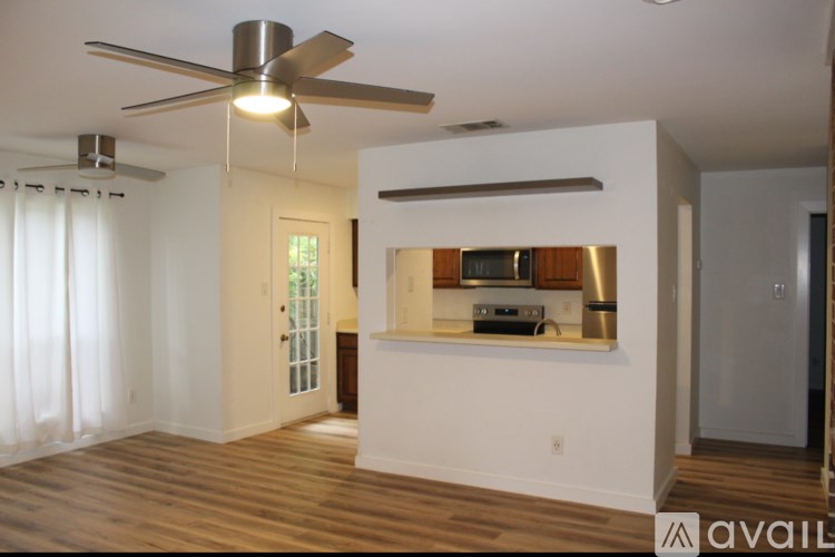 A room with a ceiling fan and a window with curtains.