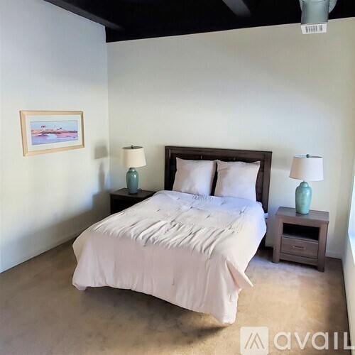 A bedroom with a large bed and two lamps.