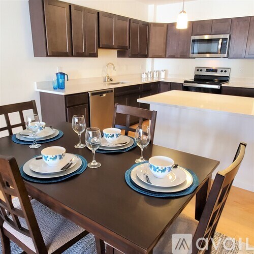 A modern kitchen with a dining table set for two.