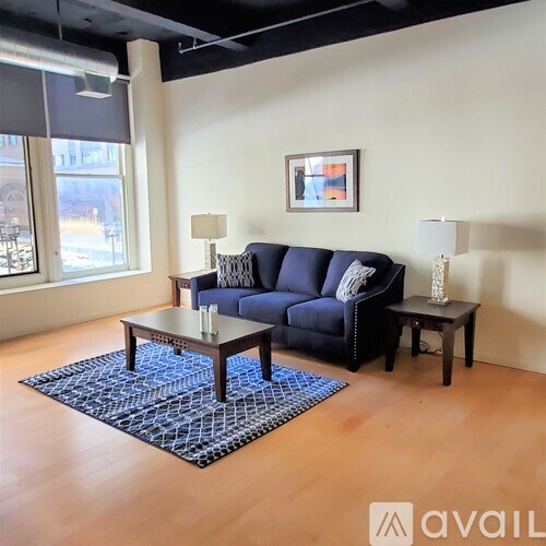 A living room with a blue couch, a coffee table, and two lamps.