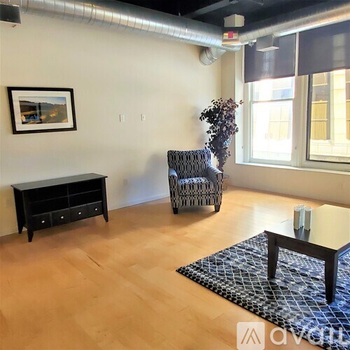 A room with a chair, a table, and a painting on the wall.