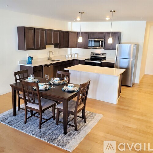 A kitchen with a table set for two with a refrigerator in the background.