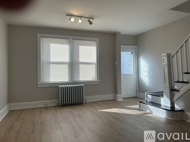 A room with a staircase and a window with blinds.