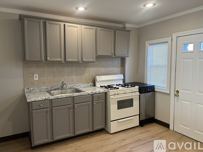 A kitchen with a stove, sink, and cabinets.