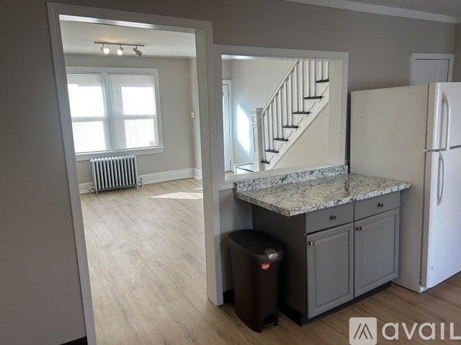 A kitchen with a marble countertop and a staircase in the background.
