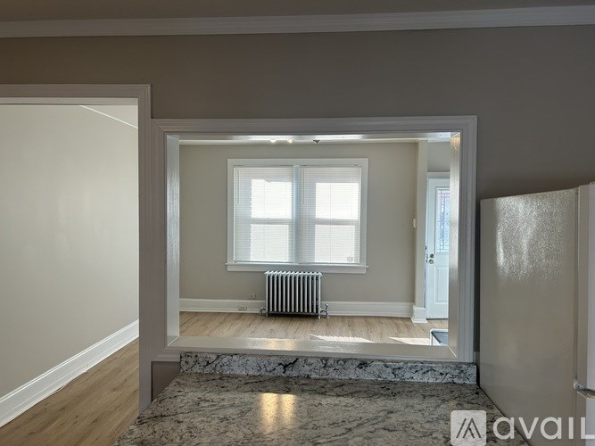 A room with a window and a radiator on the floor.