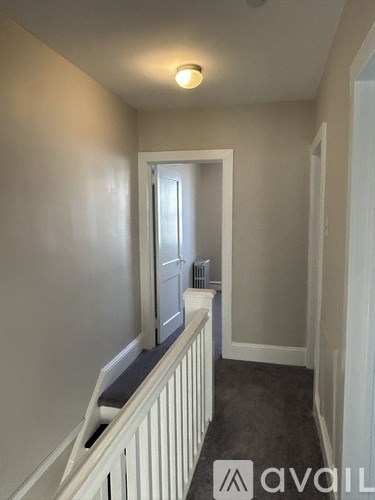 A hallway with a white railing and a door at the end.