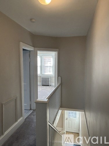 A hallway with a staircase leading to a landing with a door.