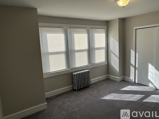 A room with a window, a radiator, and a door.