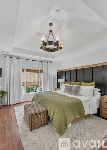 A bedroom with a large bed and a chandelier.