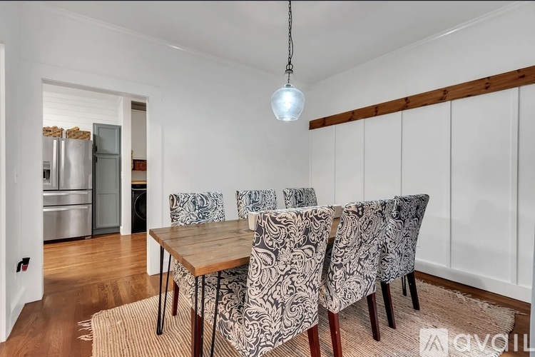 A dining room with a wooden table and chairs with a light hanging from the ceiling.