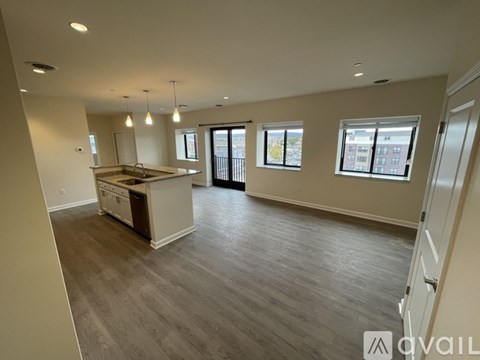 A spacious kitchen and living room with hardwood floors and large windows.