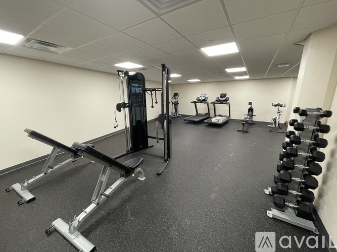 A gym with a variety of equipment including a leg press machine, a bench press, and a rowing machine.