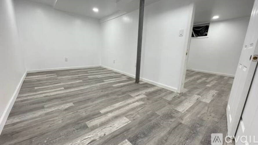 A room with wooden flooring and white walls.