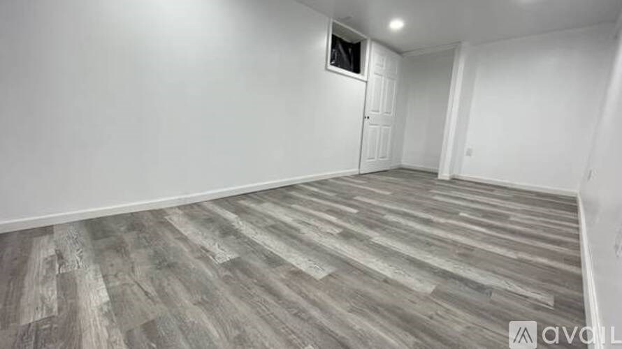 A room with wooden flooring and white walls.