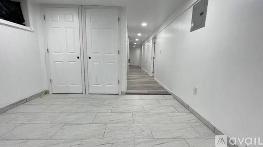A long hallway with white doors and tiled floors.