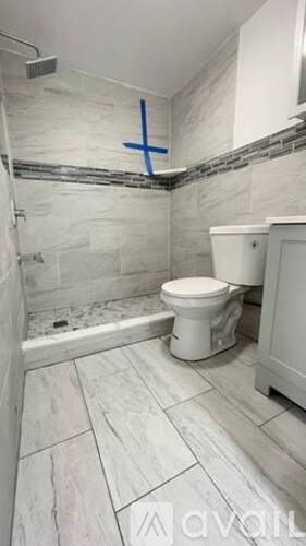 A bathroom with a toilet, sink, and tiled walls and floor.