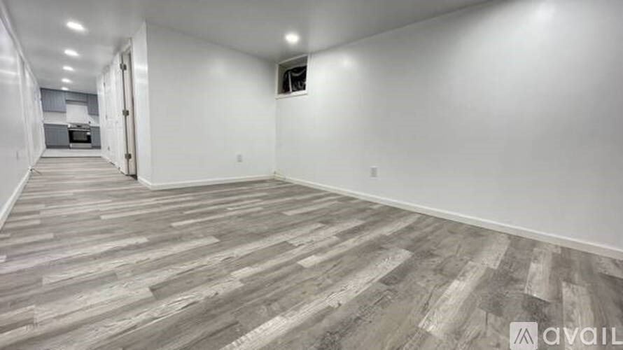 A spacious room with wooden flooring and white walls.