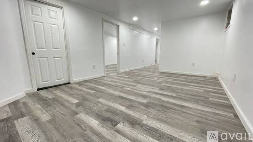 A room with wooden flooring and white walls.