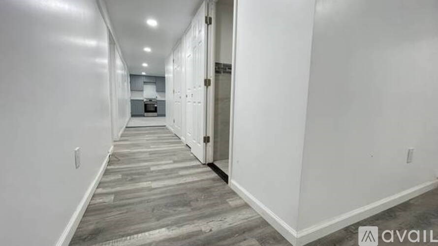 A long hallway with doors on both sides and a kitchen in the distance.