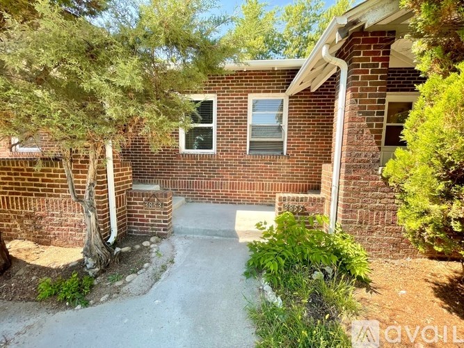 A house with a brick exterior and a tree in front.