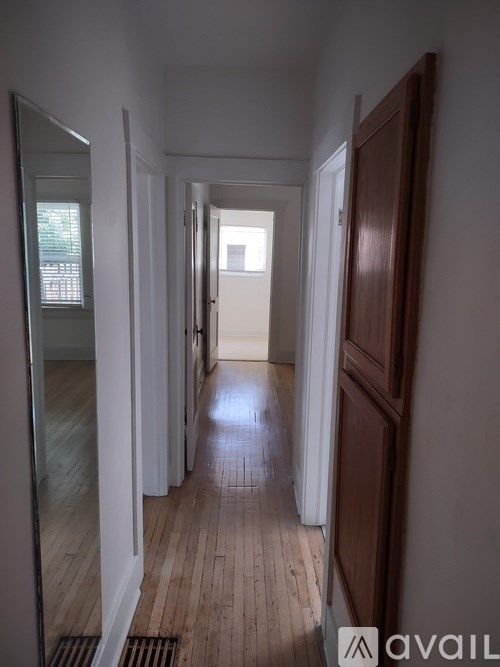 A long hallway with wooden floors and white walls.