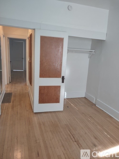 A room with a white door and a wooden floor.