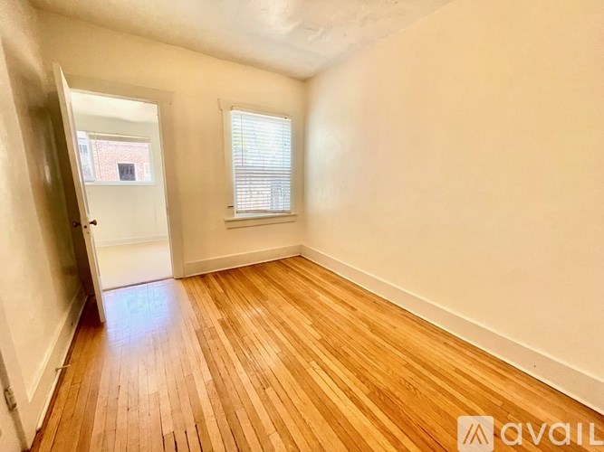 A room with wooden flooring and a window with blinds.