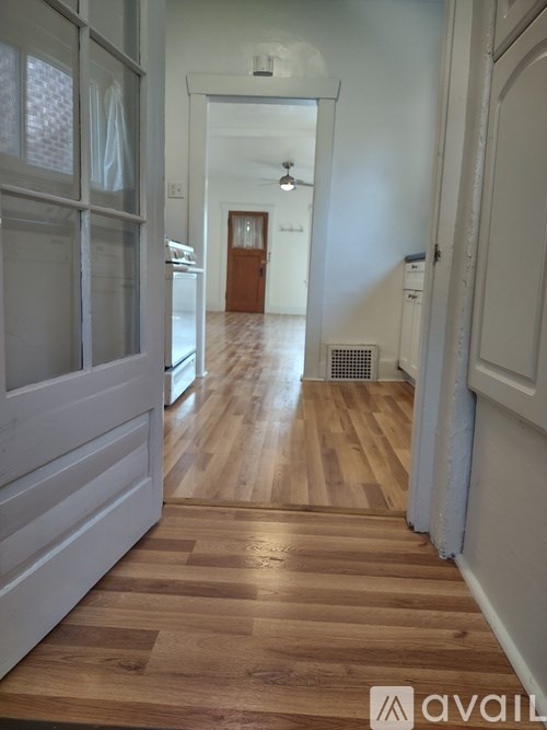 A long hallway with wood floors and white walls.