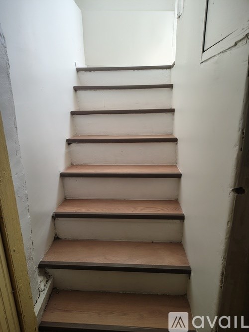Two white washing machines in a laundry room with white brick walls and pipes.