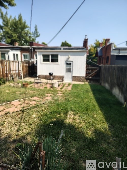 A backyard with a white house and a wooden fence.