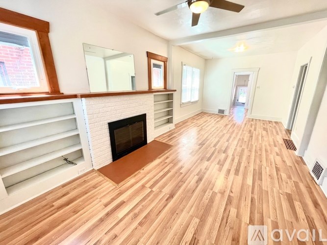 A living room with wooden flooring and a fireplace.