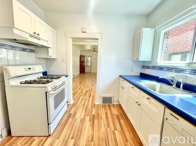 A kitchen with white appliances and wooden floors.