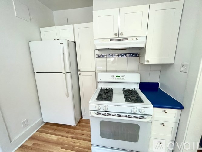 A white refrigerator and oven in a kitchen with wooden flooring.