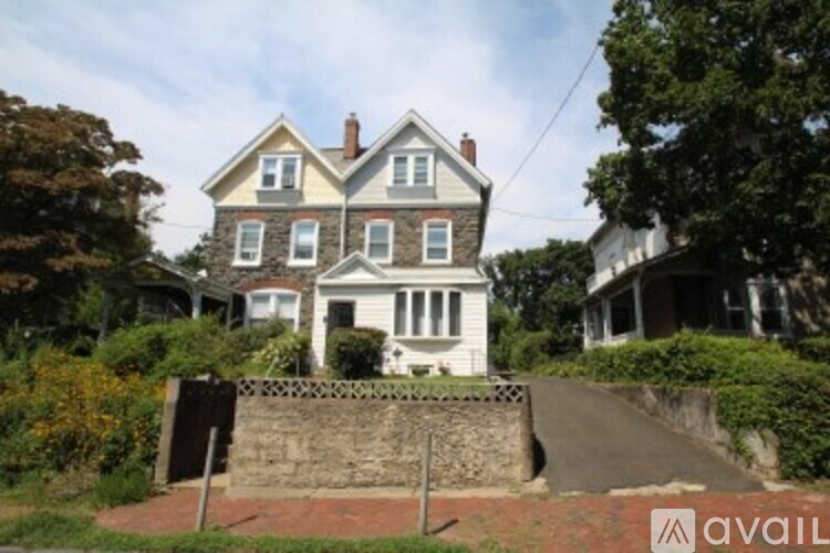 A house with a white facade and a grey roof is surrounded by greenery.