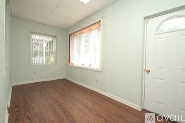 A room with a white door and a window with white blinds.