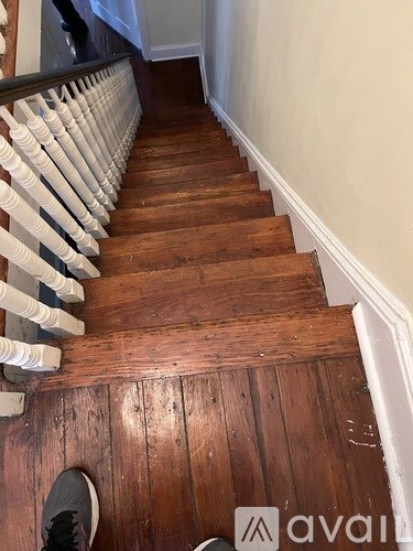 A wooden staircase with a white railing and a person's foot visible.