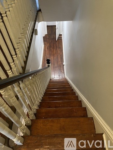 A staircase with a white balustrade and wooden steps leading to a door at the bottom.