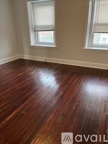 A room with wooden floors and two windows.