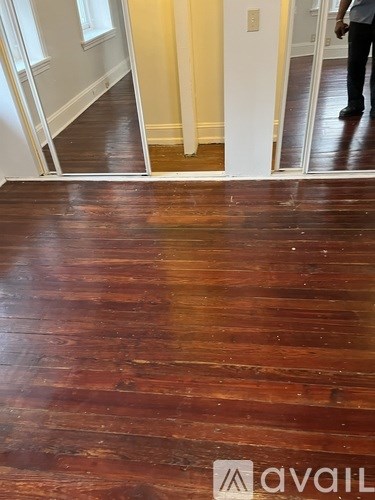 A man is standing in a room with a wooden floor.