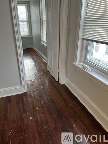 A hallway with wood floors and white walls.