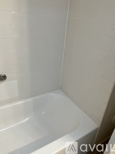 A white bathtub in a bathroom with white tiles.