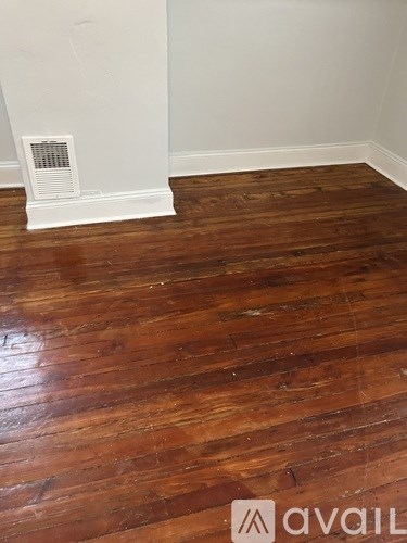 A room with wooden flooring and a white wall.